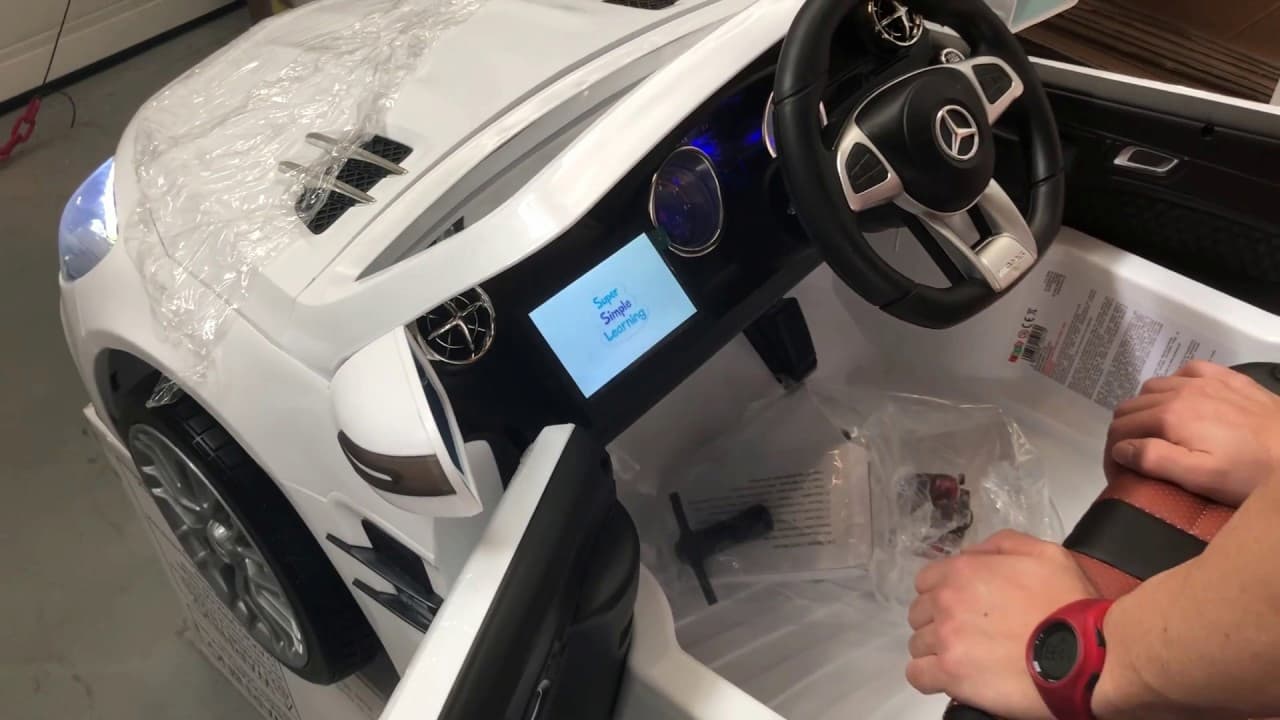 Interior de coche eléctrico infantil con volante y pantalla encendida durante revisión de batería.